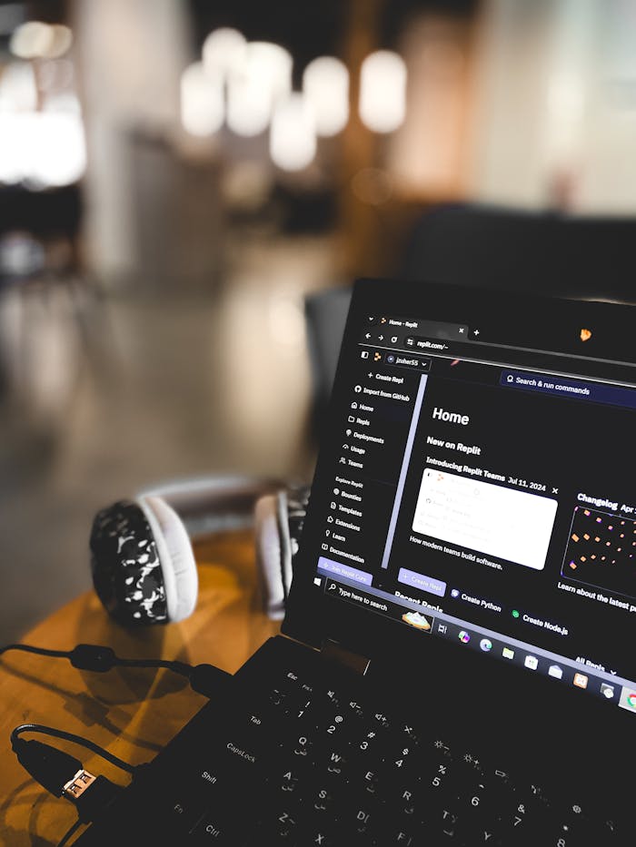 A laptop with code displayed on screen, accompanied by headphones in a cozy coffee shop setting.